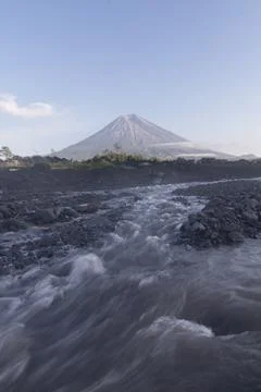 Serene river flow contrasts with active Mount Semeru in the background. Foto stock