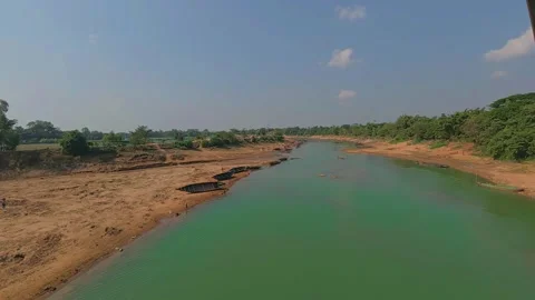 A serene river flows calmly under a clear blue sky Stock Footage 321885298