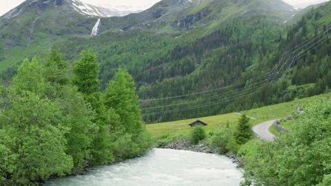 A serene river flows through an alpine valley surrounded by lush green trees Vídeo Stock 282306891