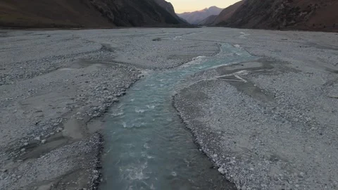 Serene river flows through rocky terrain, camera pans across the landscape Video stock 319559743