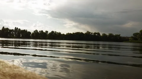 Serene river journey through lush green trees under a dramatic cloudy sky Stock Footage 337128516