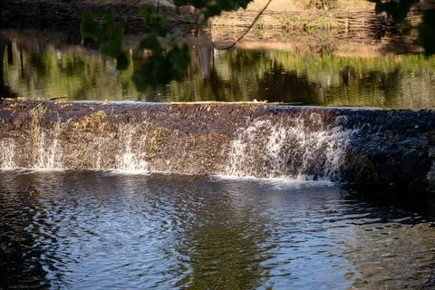 A serene river scene featuring a small stone dam Stock Photos