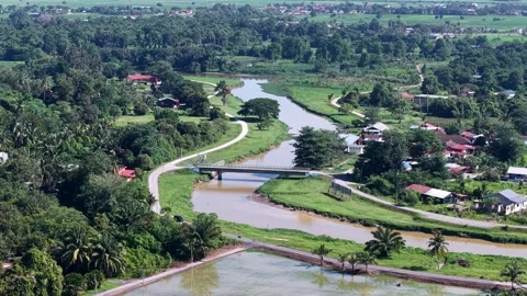 Serene River Winding Through Green Countryside with Village Homes Vídeos de archivo 344818749