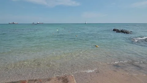 Serene Sandy Beach with Clear Blue Water and Rock Formation Stock Footage 296480362