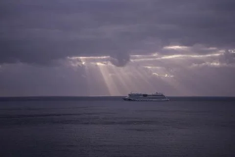 A serene scene of a cruise ship navigating through still waters under a heavi Stock-Fotos