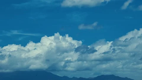 A serene scene of deep blue sky with fluffy cumulus clouds drifting gently Stock Footage 338266524