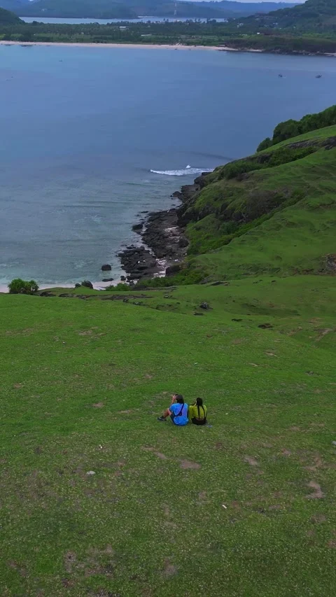 Serene scene of explorers resting on scenic cliffside overlooking bay Stockbeeldmateriaal 335091155