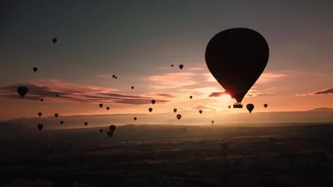 Serene scene of single hot air balloon during sunrise with distant convoy and Stock Footage 344044795