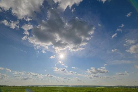 A Serene Sky Filled with Fluffy Clouds Above Lush Green Fields on a Beautiful Da Stockfoto's