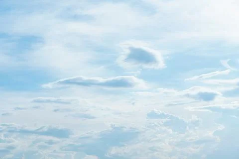 A serene sky filled with soft clouds and gentle blue hue creates peaceful atm Stock Photos