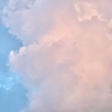A serene sky scene featuring a patchwork of soft blue, pale pink, and grey .. Stock Photos