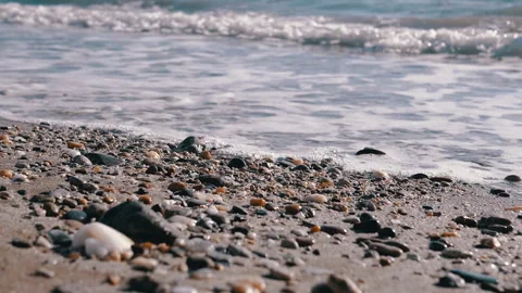 The serene sounds of beach waves gently crashing against colorful pebbles and Stock Footage 313870543