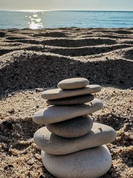Serene Stone Stack on a Beach Balanced zen stones on sandy beach with sunli.. Stock Photos