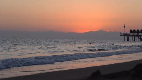 A serene sunset at the beach, with gentle waves lapping at the shore and a Stock-Footage 317905482