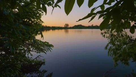 Serene Sunset Lake View Framed by Trees Stock Footage 326373786