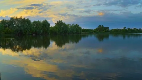 Serene Sunset or Sunrise over Calm Lake Water with Forest Reflection Stock Footage 326377372