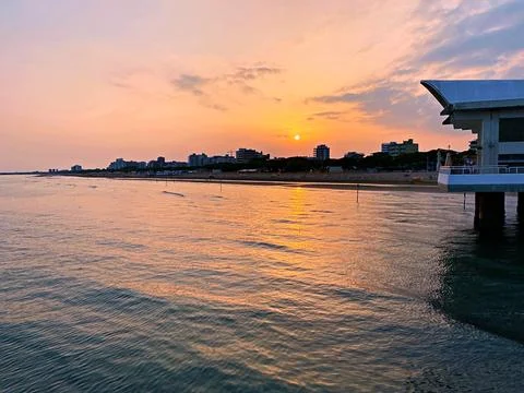 Serene Sunset Over the Ocean With Reflections at Coastal Boardwalk in Summer Stock Photos