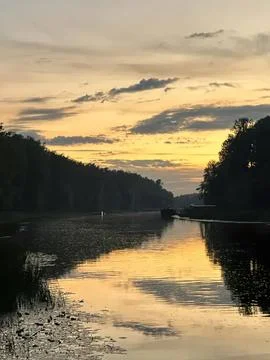 Serene sunset over river with trees and cloudy sky Stock Photos