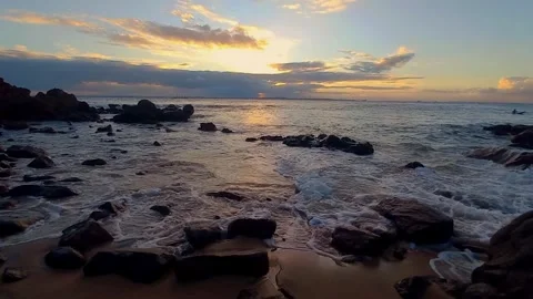 Serene sunset on a sandy beach with gentle waves lapping the shore during the go Stock Footage 320056872