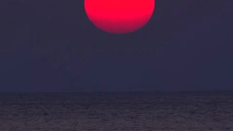 Serene sunset view over ocean with large red sun sinking into horizon Stock Footage 271475280
