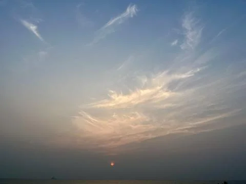Serene Sunset with Wispy Clouds Over Calm Ocean Horizon Stock-Fotos