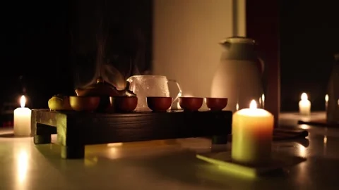 A serene tea setup featuring steaming clay cups and a glass teapot on a wooden t Video stock 299386064