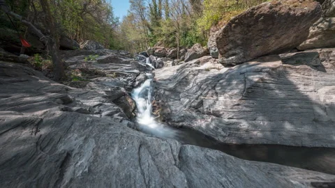 Serene Time-lapse of Waterfall in Scenic Rocky Forest Environment Stockbeeldmateriaal 334716612