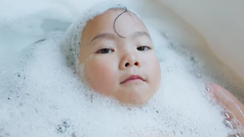 Serene toddler relaxes while bathing in a tub full of bubbles Stock Footage 339047629