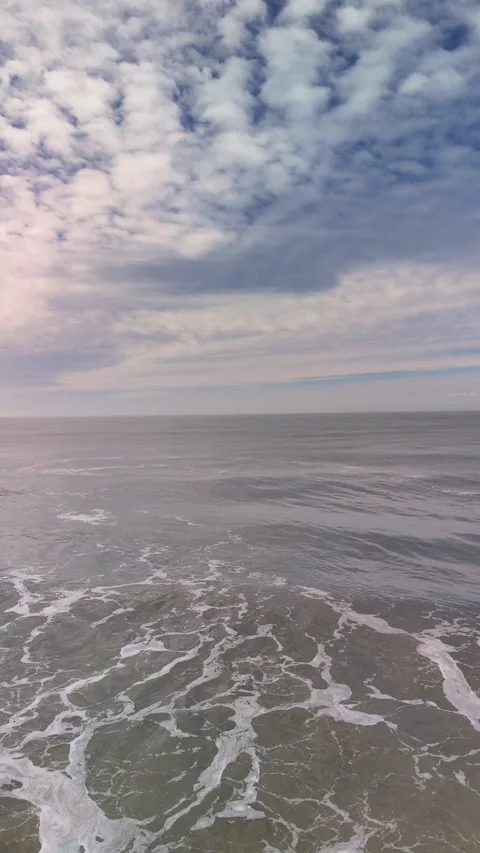 Serene Vertical View of Gentle Ocean Waves Under a Cloudy Sky at the Horizon Stock Footage 325664685
