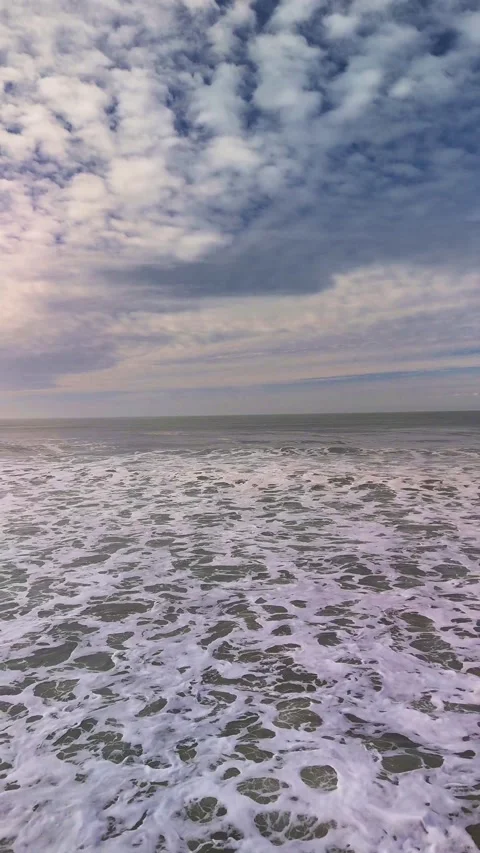 Serene Vertical View of Gentle Ocean Waves Under a Cloudy Sky at the Horizon Stock Footage 325664689
