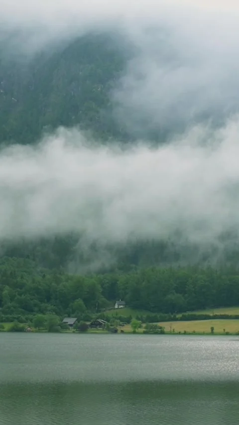 A serene vertical view of a mist-covered lake with lush green forests and hills Stock-Footage 287318581