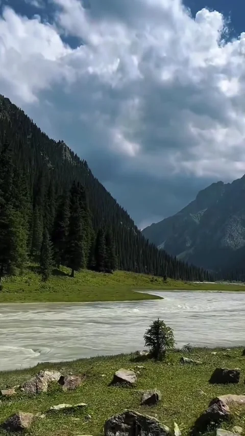 A serene video showcasing a river flowing through a mountainous landscape with Vidéo 333021666