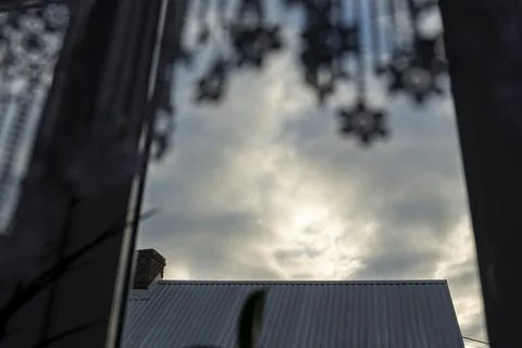 A serene view from inside a home featuring a cloudy sky behind a metal roof, Stock-Fotos