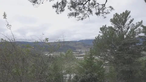 A serene view of a landscape featuring trees, mountains, and a cloudy sky Stock-Footage 332613500