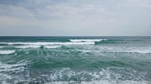 A serene view of ocean waves gently rolling towards the shore under a cloudy sky Stock Footage 285636042