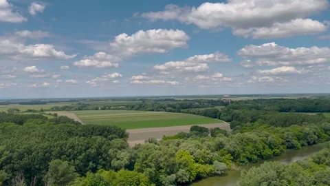 A serene view of a river surrounded by lush green forests and distant hills. Stock Footage 299938086