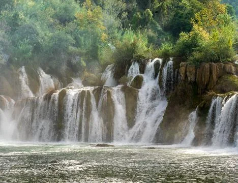 Serene waterfall cascades down multiple levels of lush Stock Photos