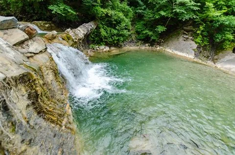 Serene waterfall cascading into emerald pool in forest Stock Photos