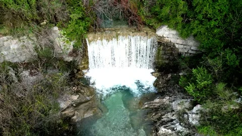 A Serene Waterfall Gracefully Cascades Down Over Rocks, Completely Surrounded by Stock Footage 300474066