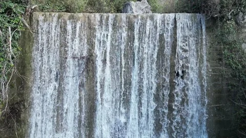 A Serene Waterfall Gracefully Cascades Down Over Rocks, Completely Surrounded by Stock Footage 300474247