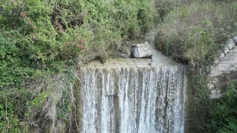 A Serene Waterfall Gracefully Cascades Down Over Rocks, Completely Surrounded by Stock Footage 300474436