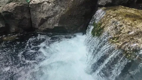 Serene Waterfall Surrounded by Rocks and Lush Greenery Stock Footage 315469475