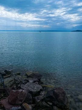 Serene waterscape with sailboat under soft sky calm sailing ambiance Stock Photos