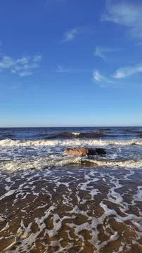 Serene Waves Rolling on Sandy Beach Under Blue Sky Stock Photos