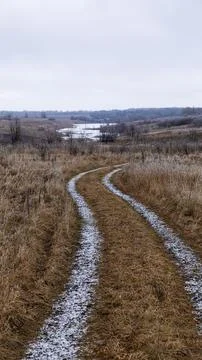 A serene, winding path gently meanders through lush grasslands near a tranqui Stock Photos