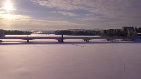 A serene winter landscape featuring a bridge crossing a frozen river, with .. Stock Footage 287073944