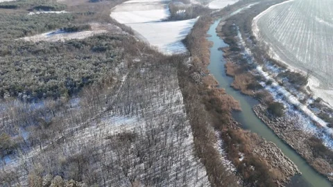 Serene Winter River Meandering Through Snow-Covered Fields and Forest Stock Footage 281113181