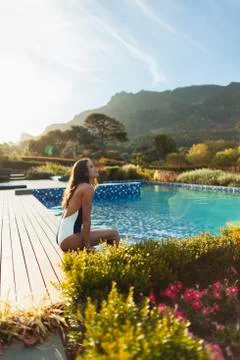 Serene woman in bathing suit relaxing at idyllic, tranquil swimming pool, Cape Stock Photos