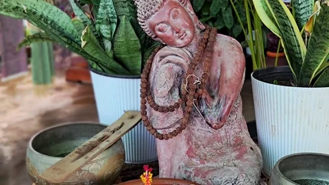 A serene Zen altar features a Resting Buddha with a mala, placed behind a clay b 库存影片 333611246