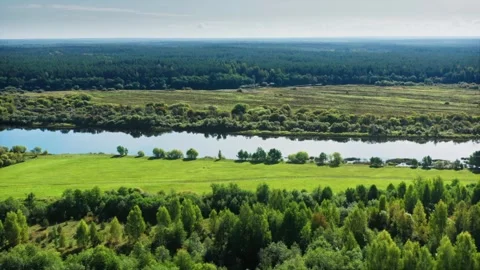 Serenity in Reflection, Smooth Riverbed Amidst Lush Pastures and Hay Fields Stock Footage 257781073